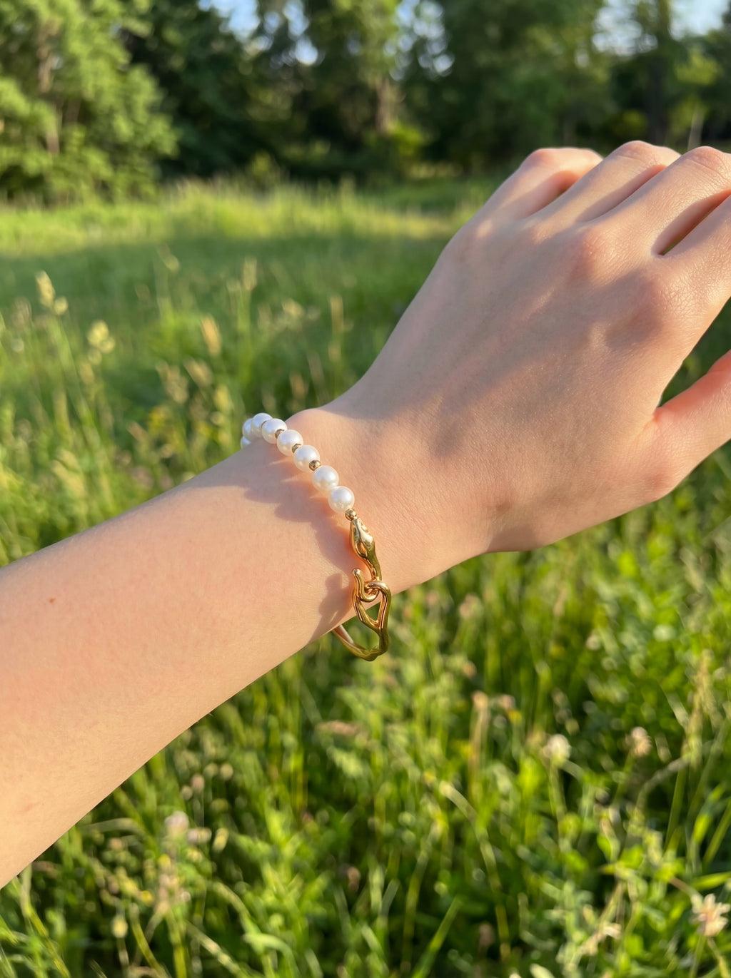 Hand wearing a bracelet with a green field background