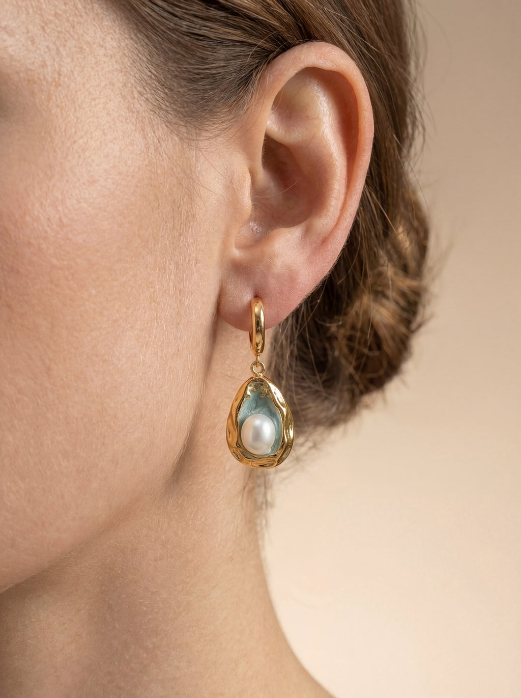 Person wearing gold earrings with pearls 