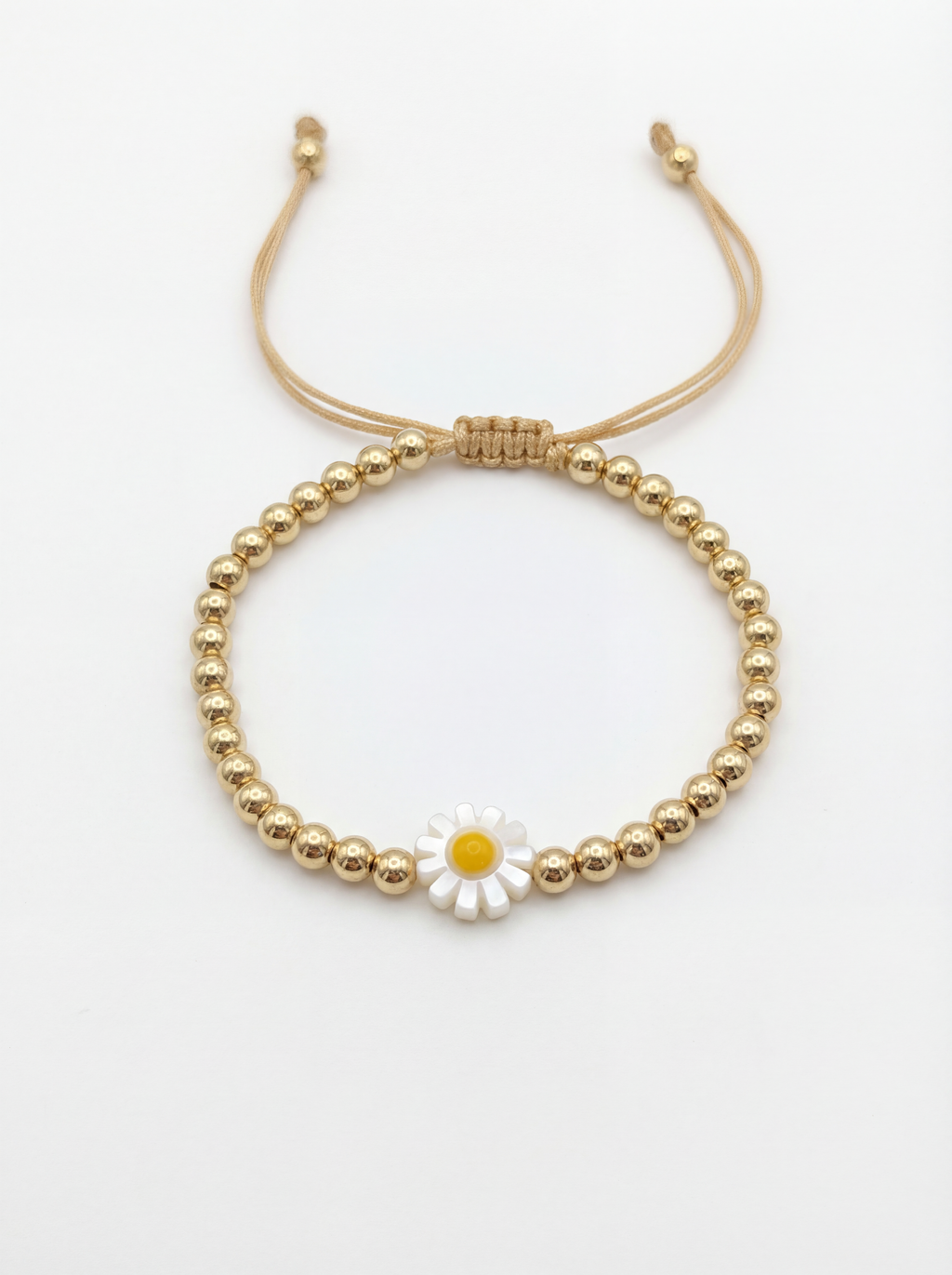 Gold beaded bracelet with a daisy charm on a white background