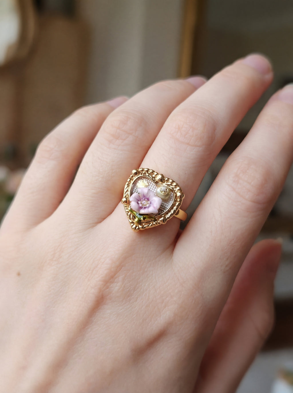 Gold ring with a pink gemstone on a hand against a blurred background