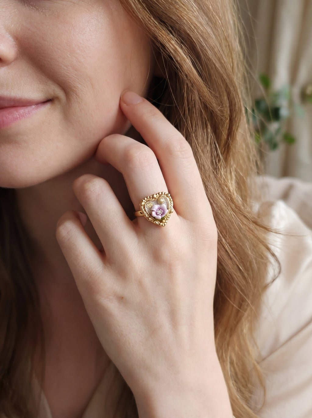 Close-up of a woman wearing a gold ring with a heart-shaped gemstone.