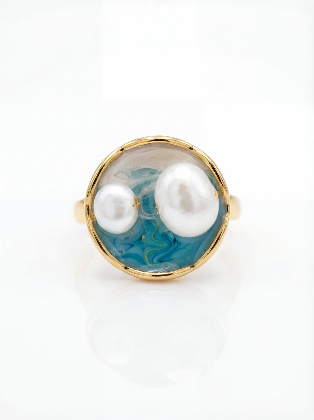 Ring with two pearls and a blue marbled background on a white background