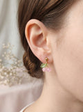 Close-up of an ear wearing a pink floral earring with a blurred background