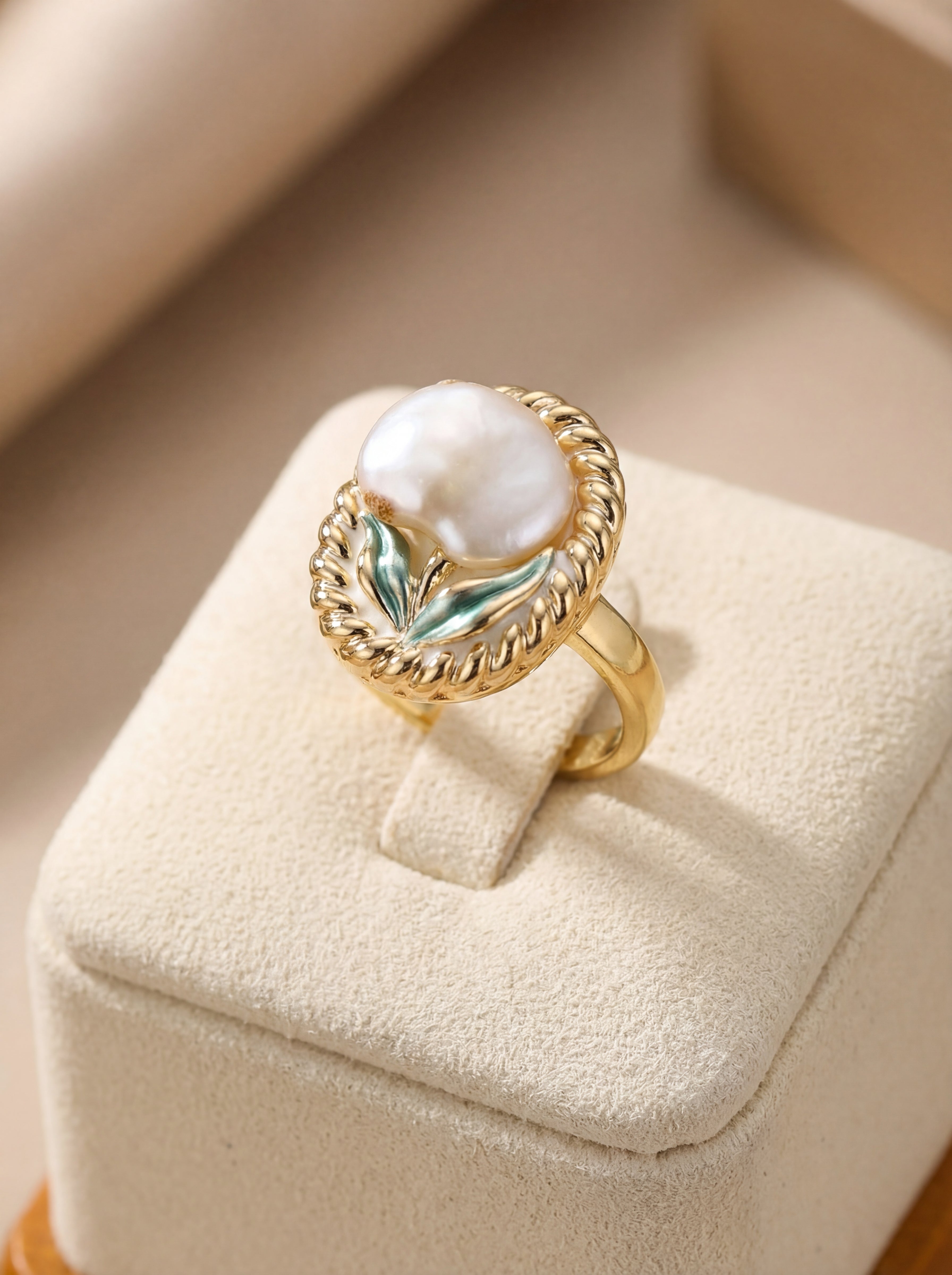 Gold ring with a large pearl on a beige jewelry box