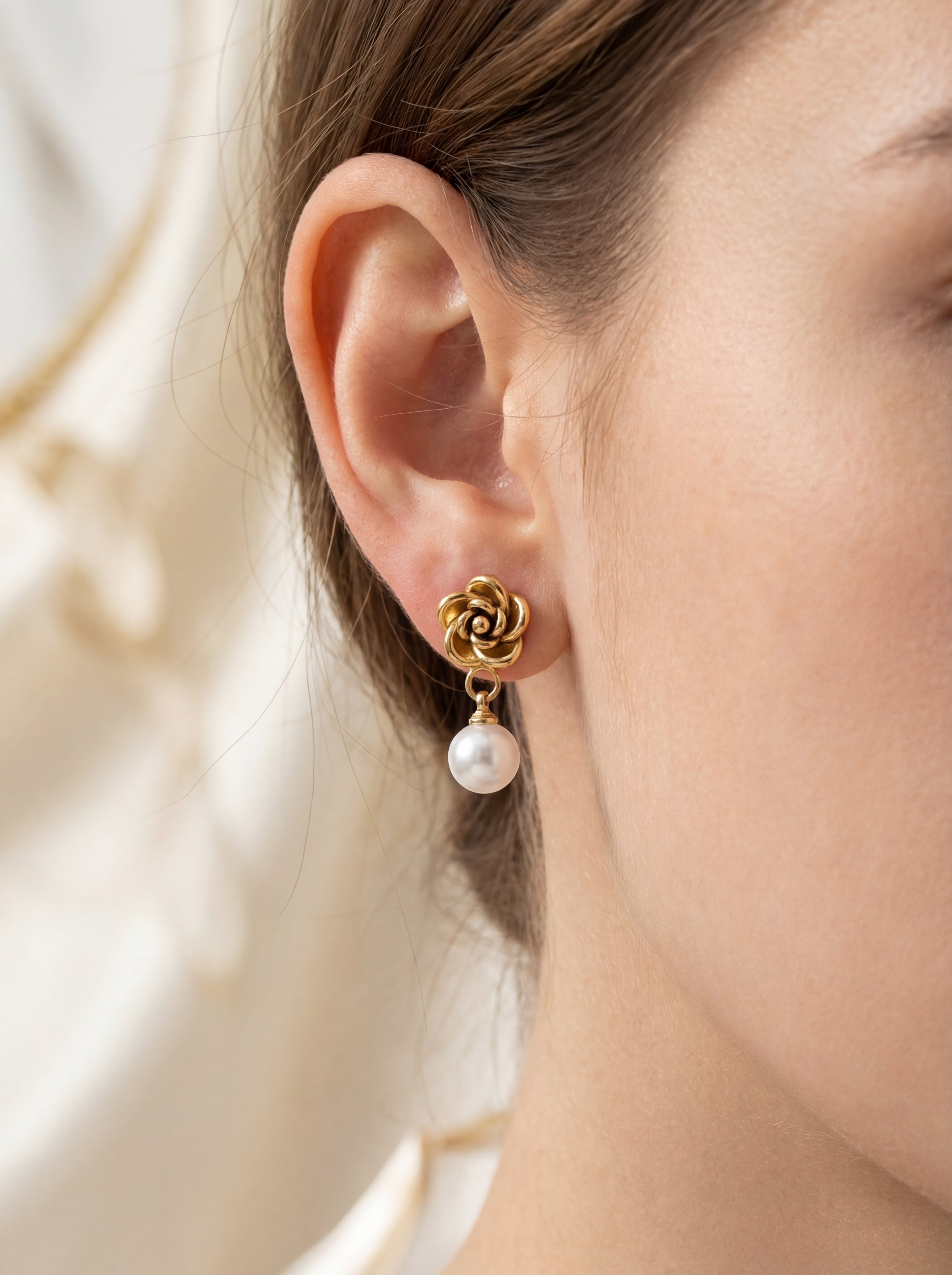 Person wearing gold flower-shaped earrings