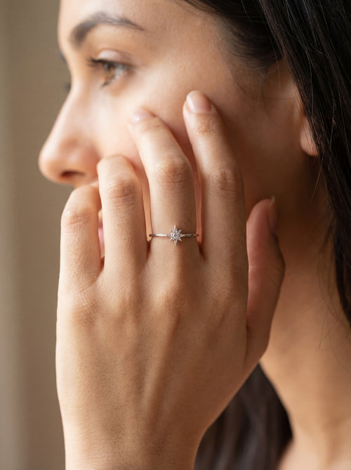 Close-up of a woman's hand wearing a diamond ring with a blurred background