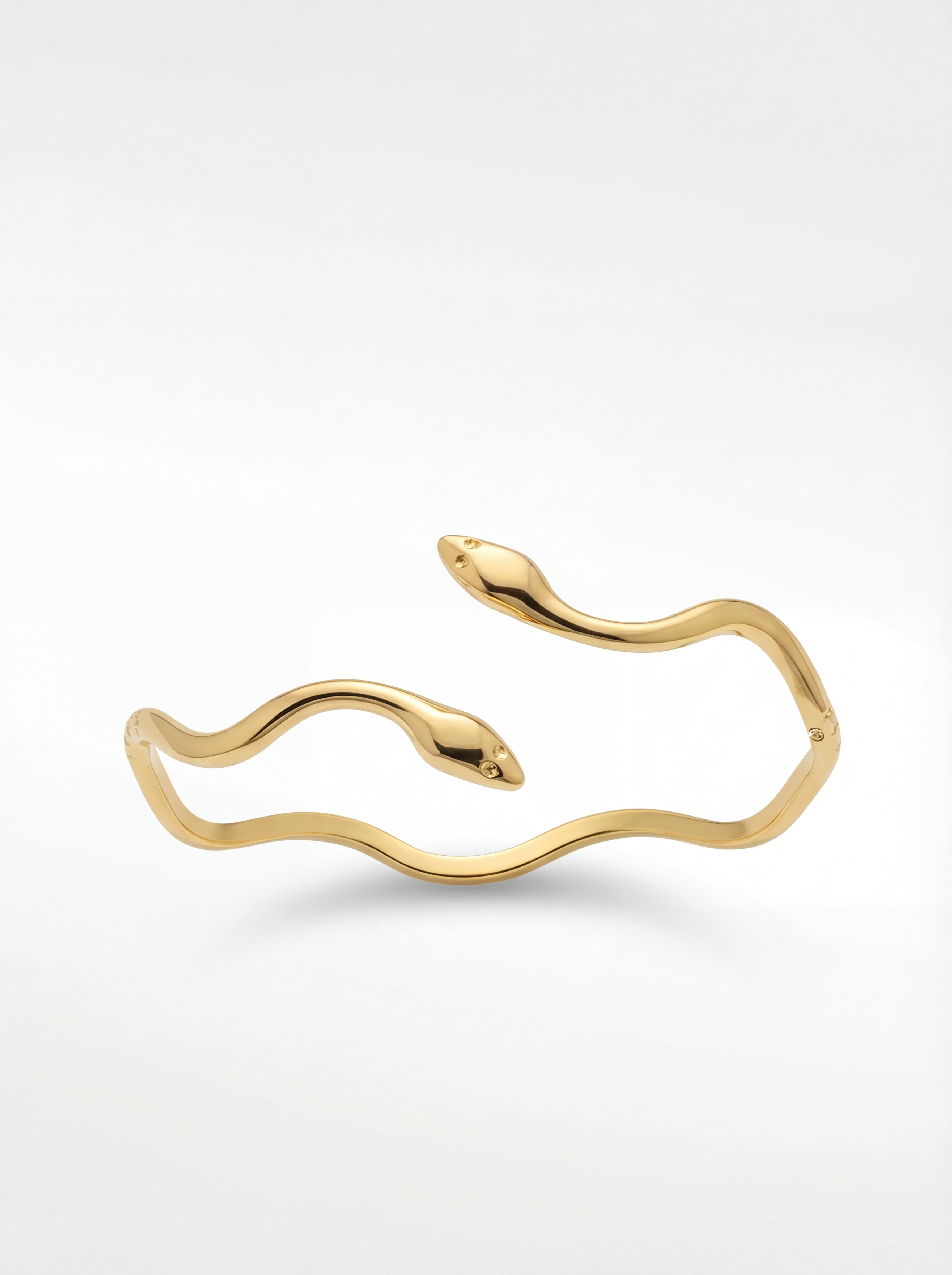 Gold bracelet on a white pedestal with a white background
