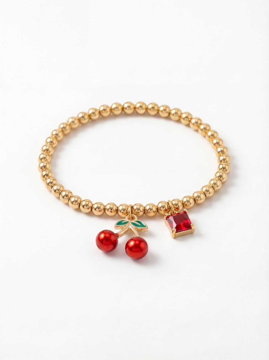 Gold beaded bracelet with cherry and gemstone charms on a white background