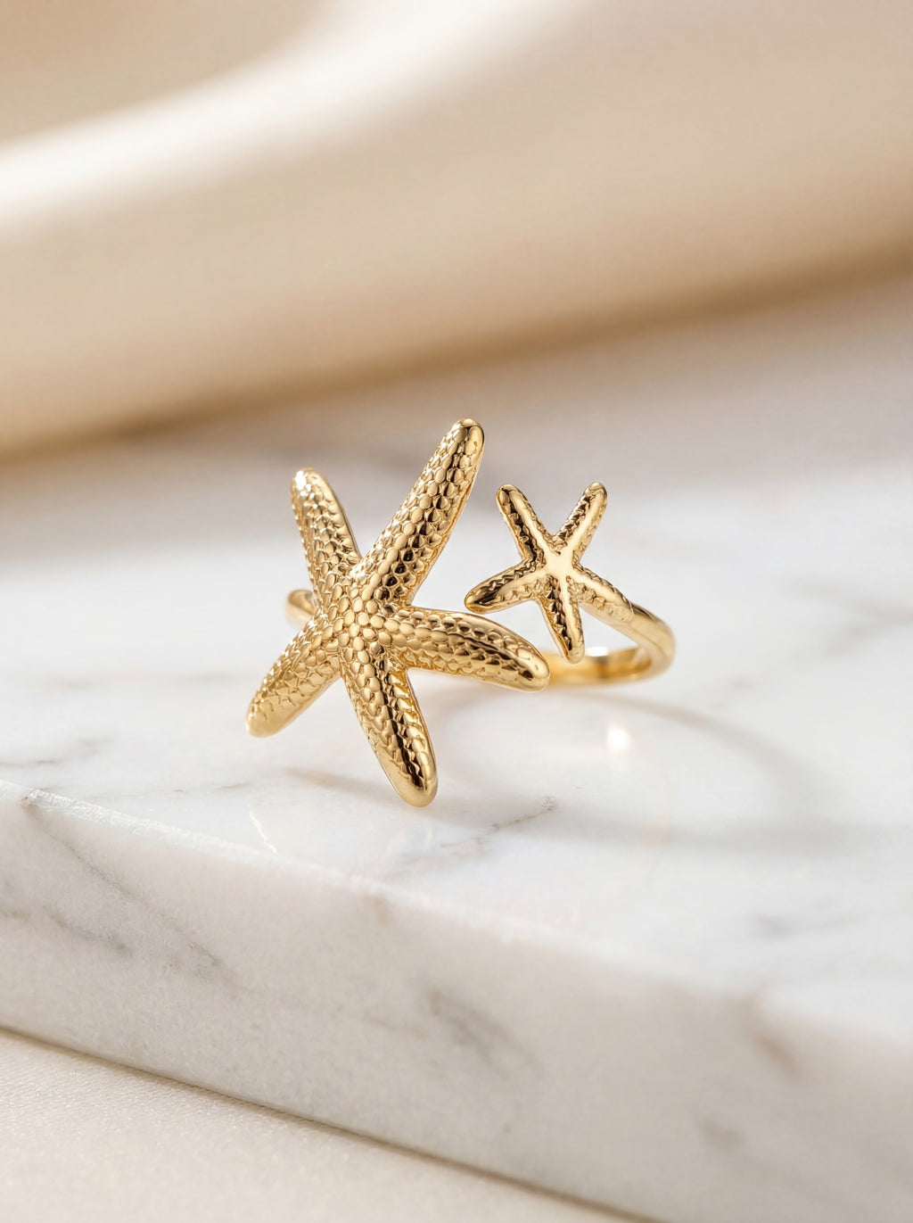 Gold starfish-shaped ring on a marble surface