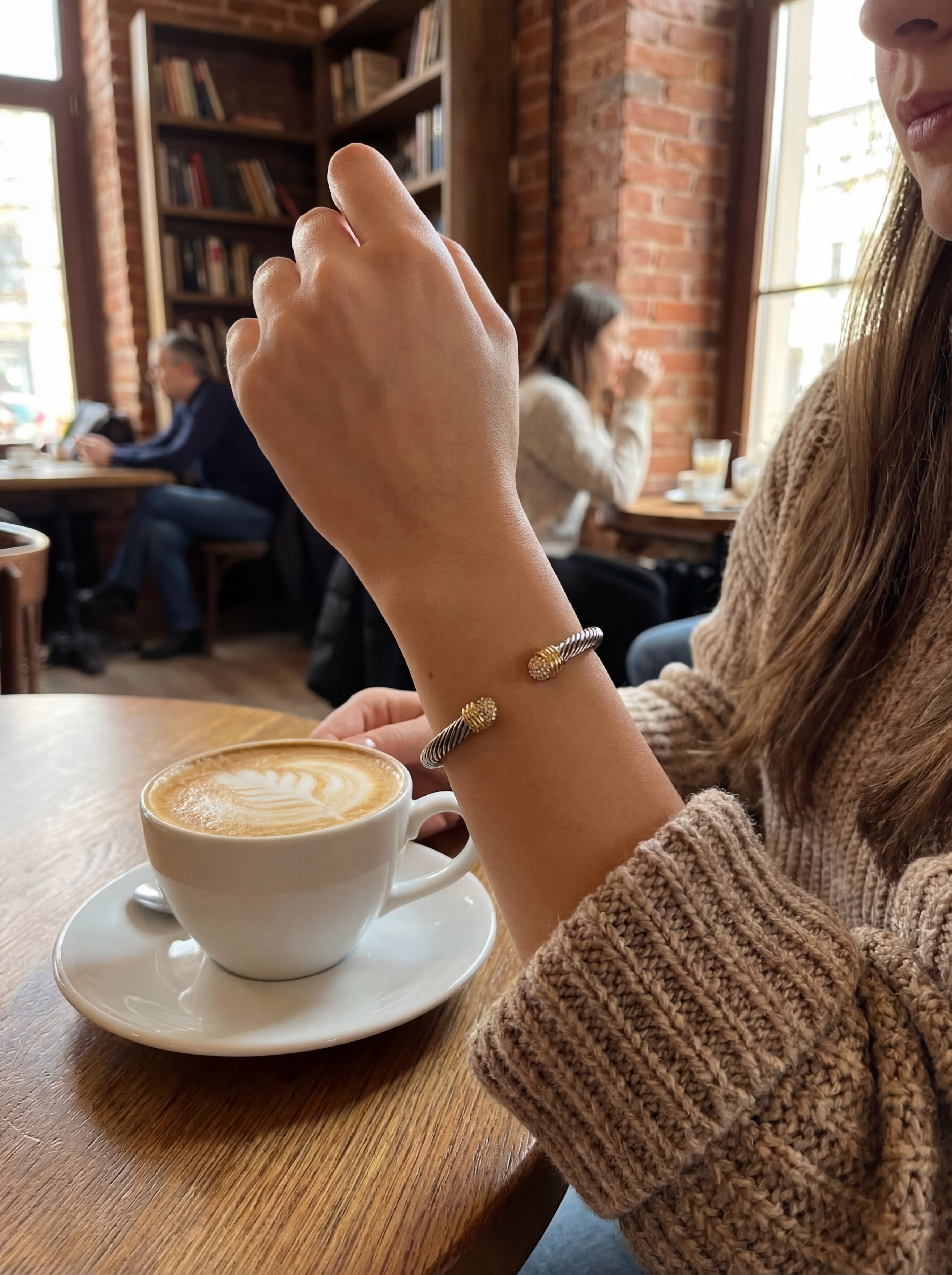 Person holding a cup of coffee with a blurred cafe background