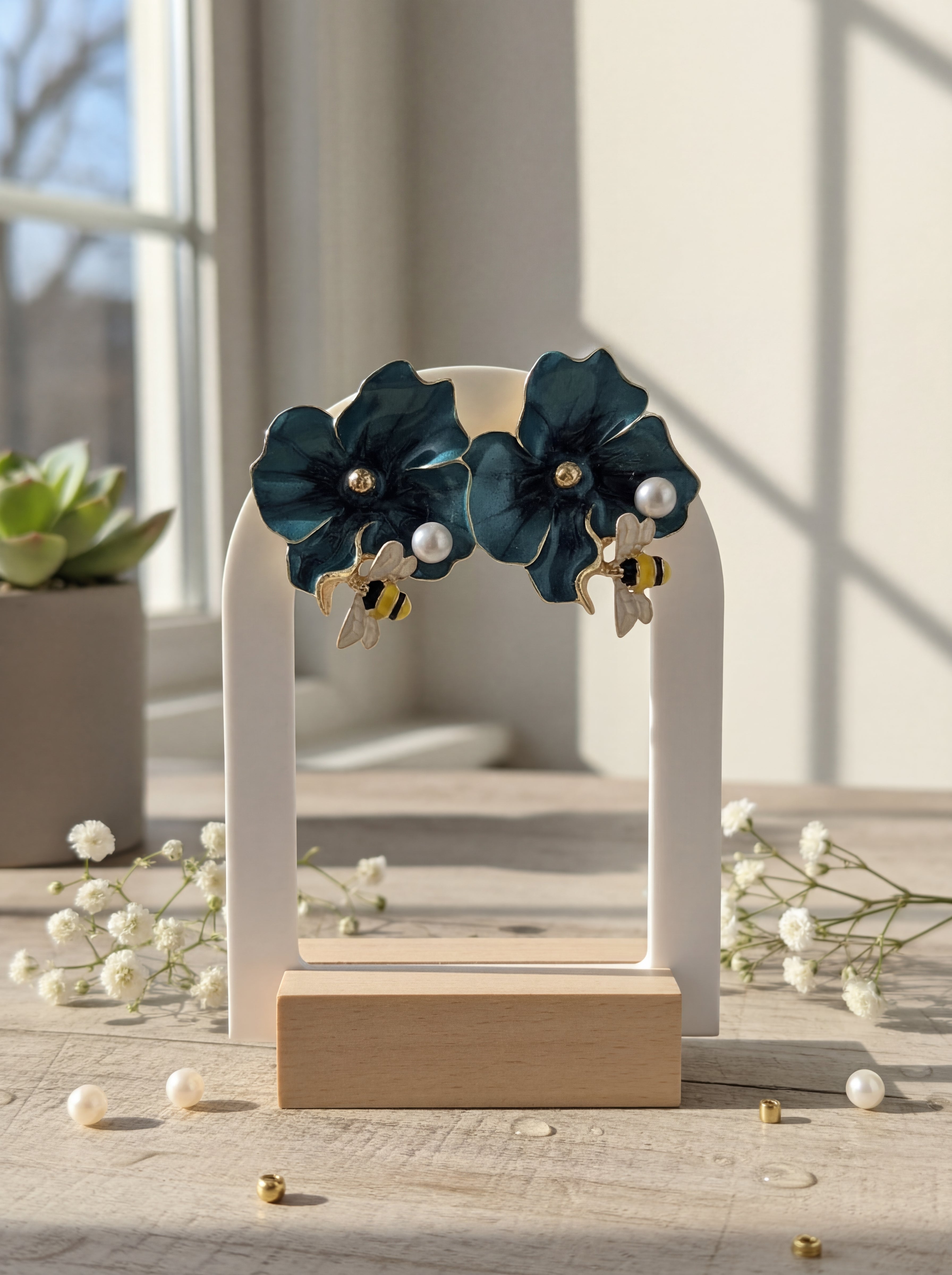 Pair of dark blue floral earrings on a white stand with a blurred indoor background