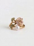 Gold ring with a pearl and gemstone on a light gray background