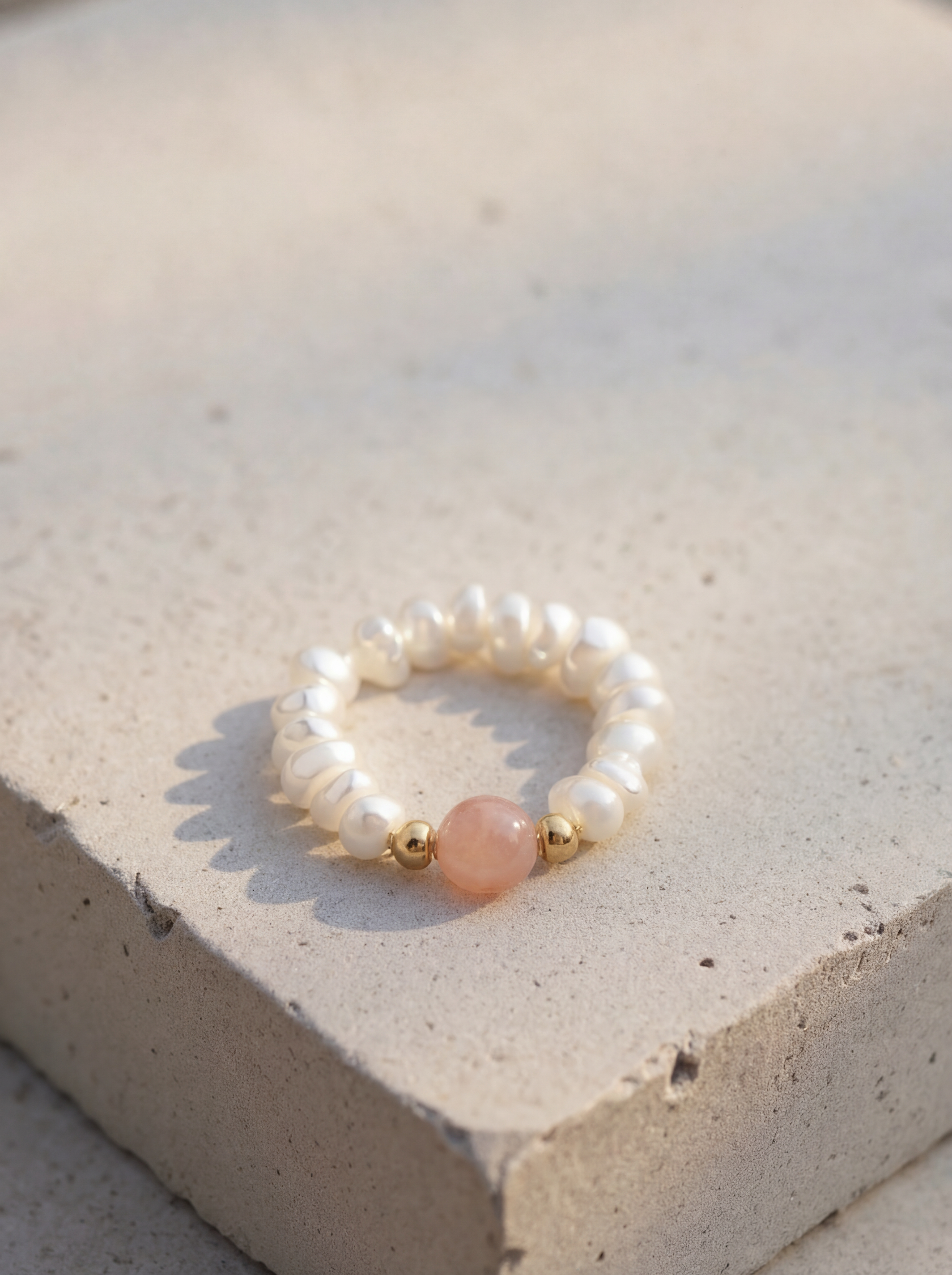 Pearl bracelet with pink stone on a concrete surface