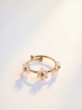 Gold ring with pink gemstones on a light background