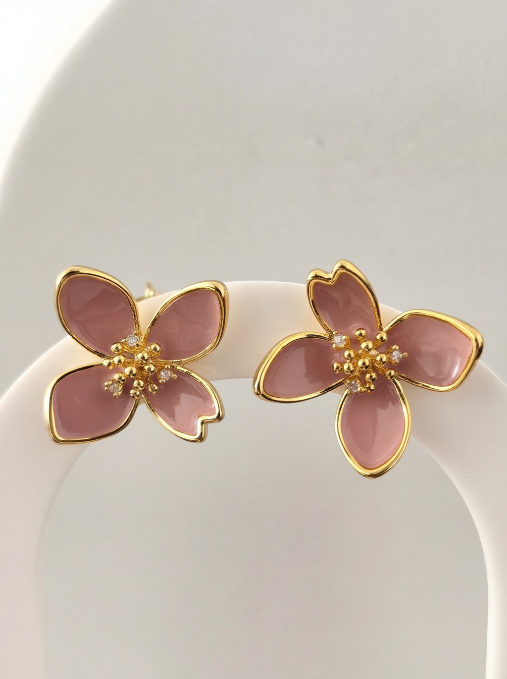 Pink flower-shaped earrings with gold accents on a white background
