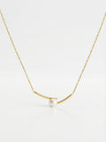 Gold necklace with a single pearl on a white background