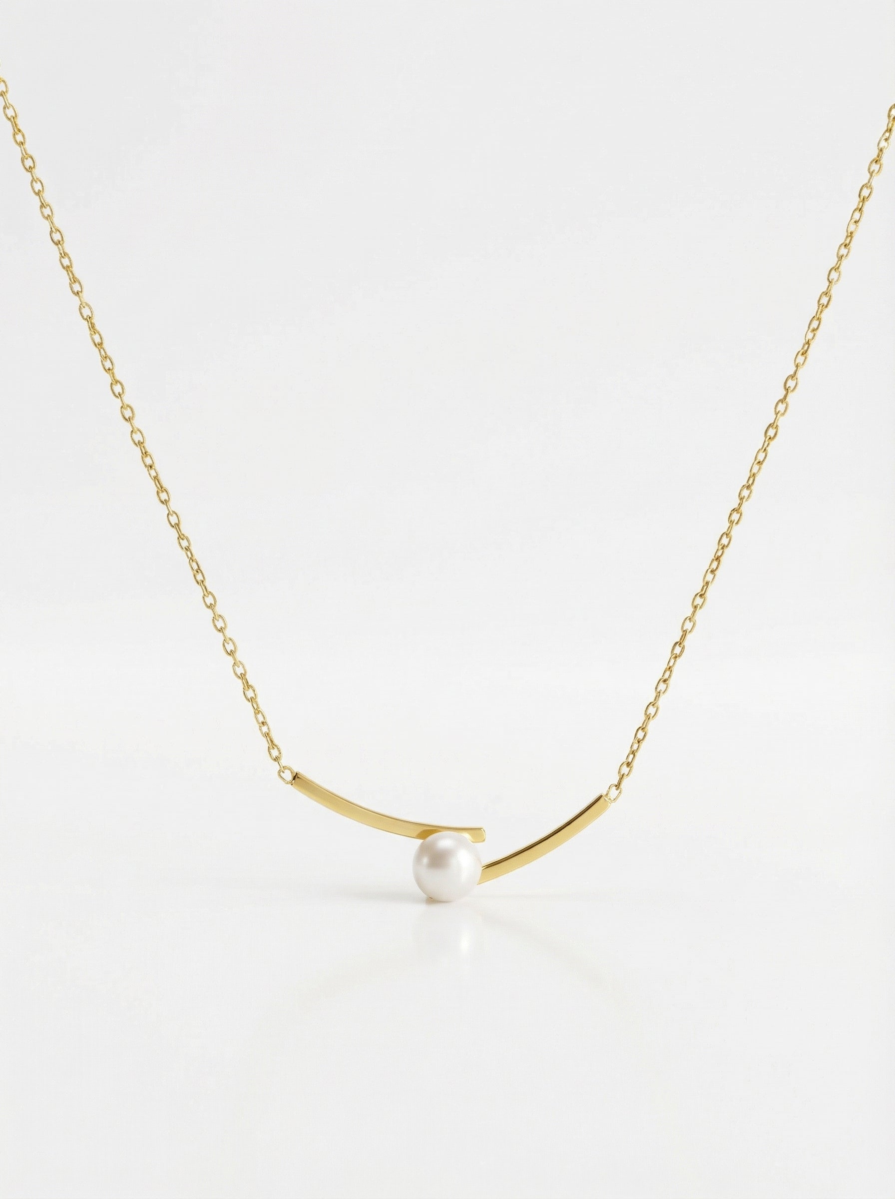 Gold necklace with a single pearl on a white background
