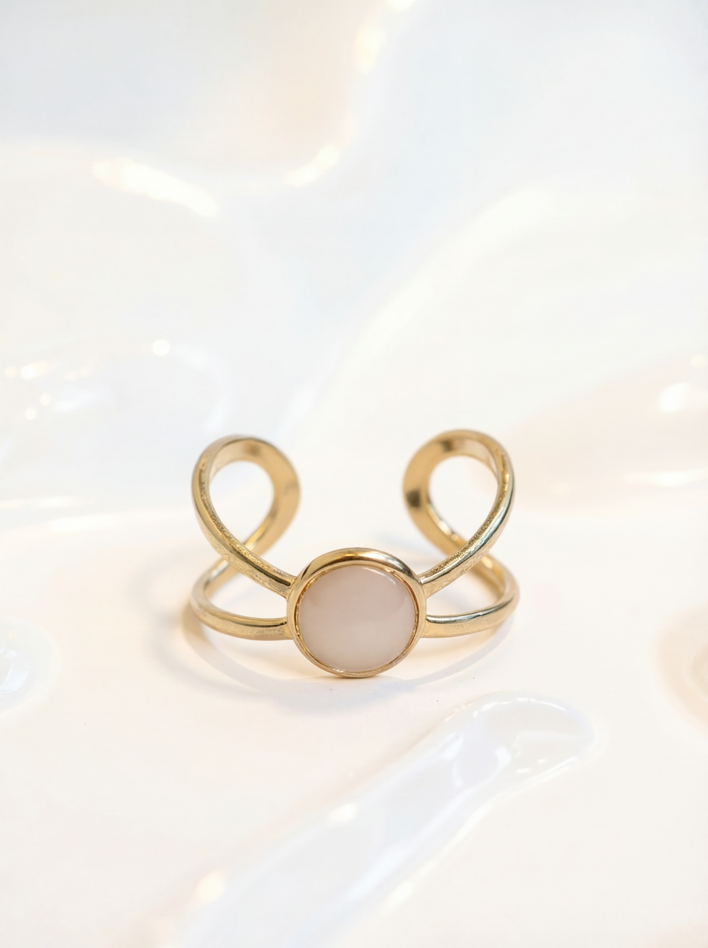 Gold ring with a beige stone on a light background