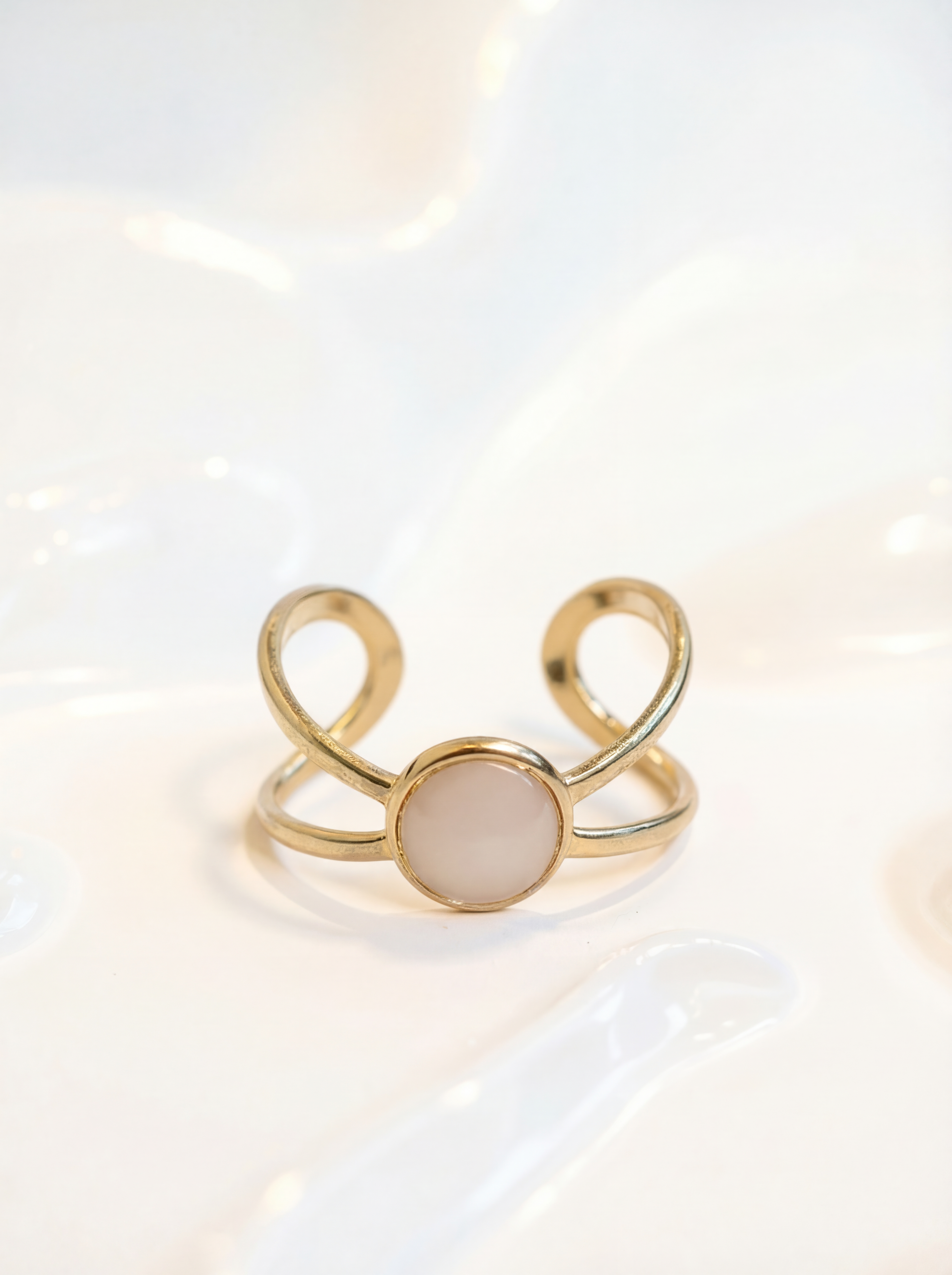 Gold ring with a beige stone on a light background