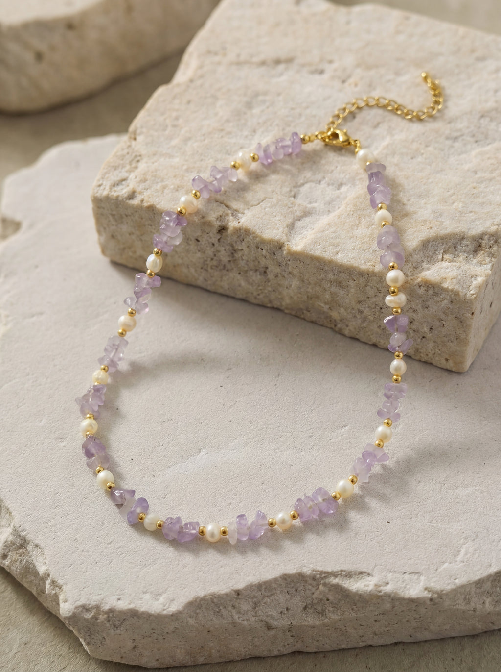 Necklace with purple and gold beads on a stone surface