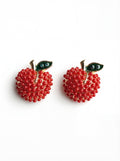 Red beaded apple earrings with gold stems and green leaves on a white background