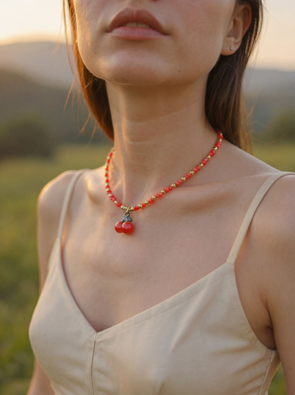 Woman wearing a red beaded necklace with cherry pendants in a natural setting