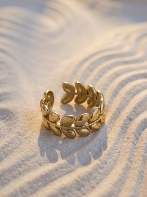 Gold leaf ring on a textured beige surface