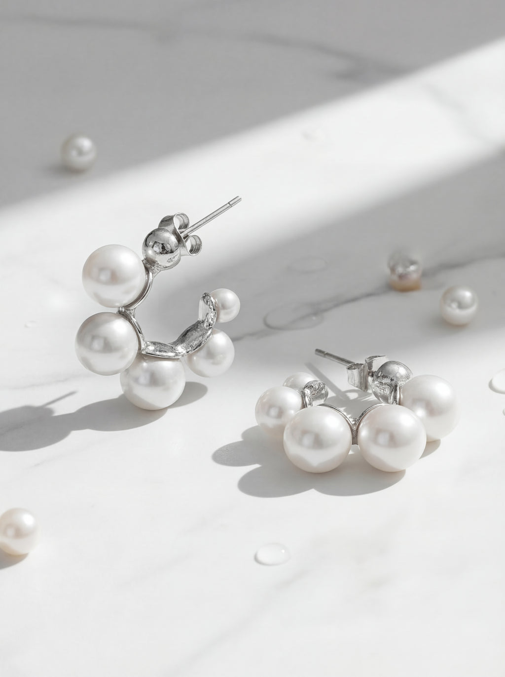 Pearl earrings on a light surface with soft shadows