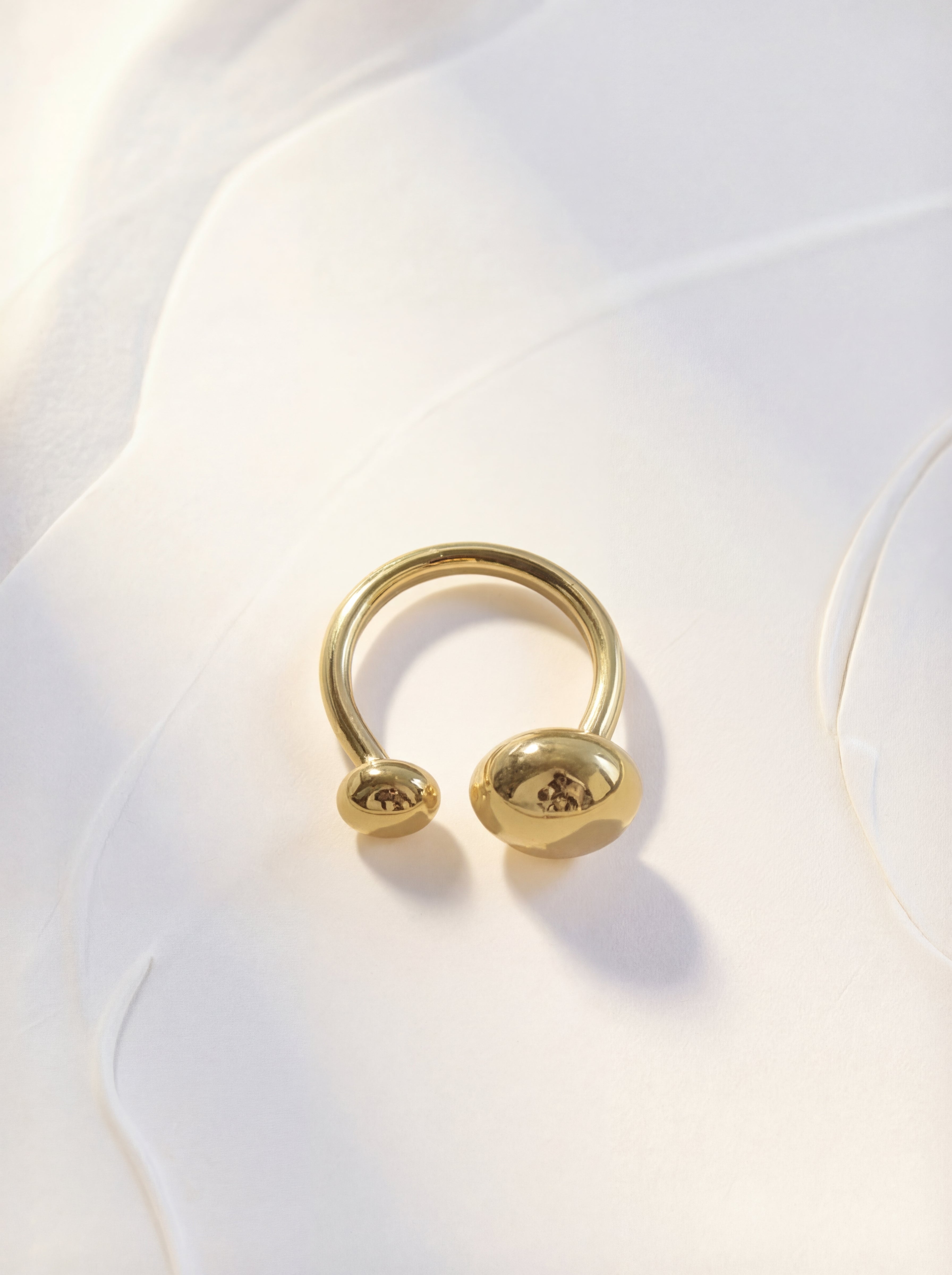 Gold ring with a unique design on a white fabric background