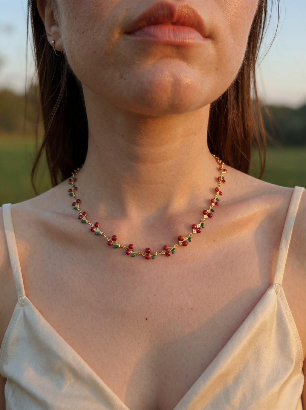 Close-up of a woman wearing a colorful beaded necklace with a blurred natural background