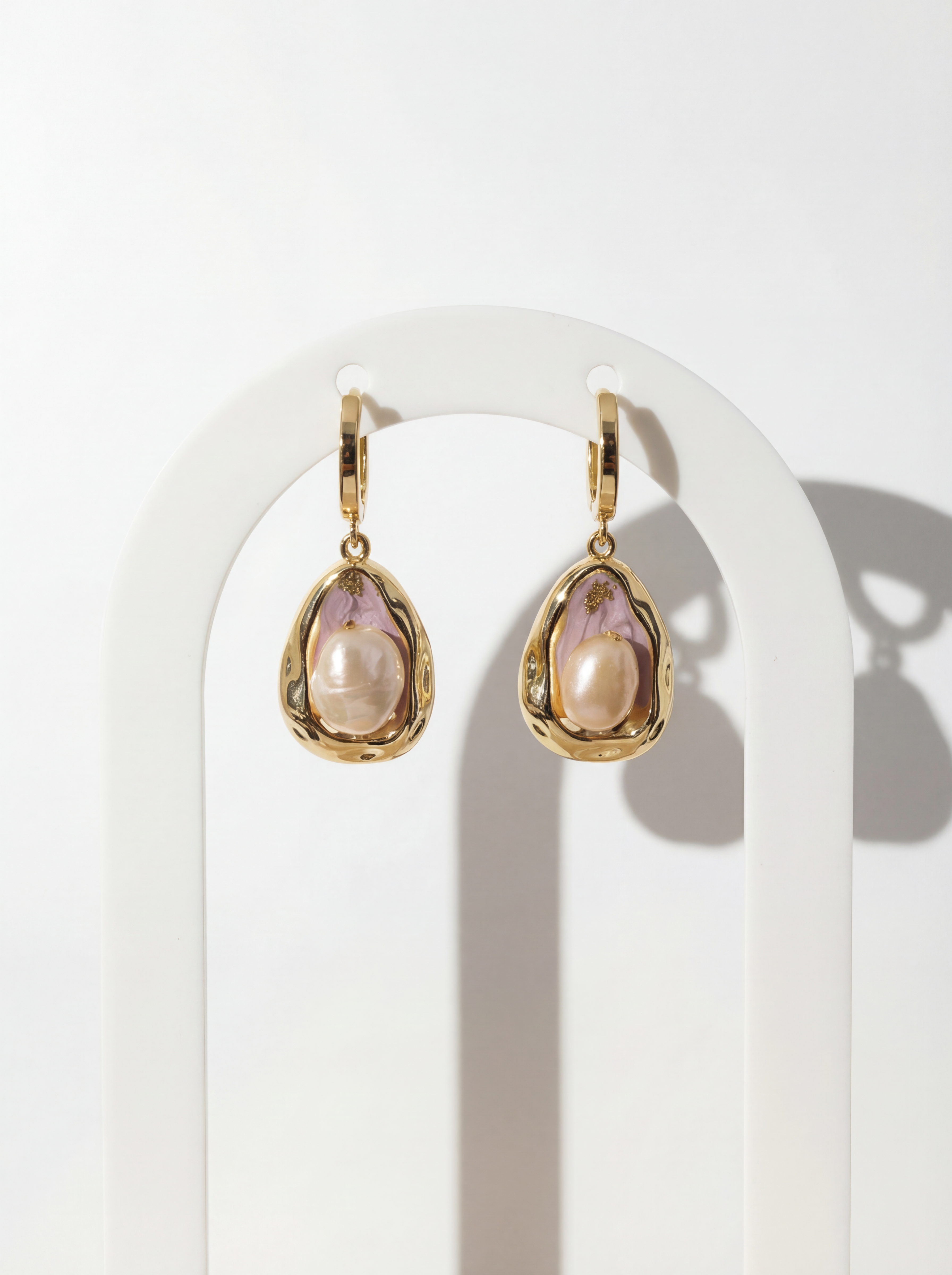 Gold earrings with pink gemstones on a white background