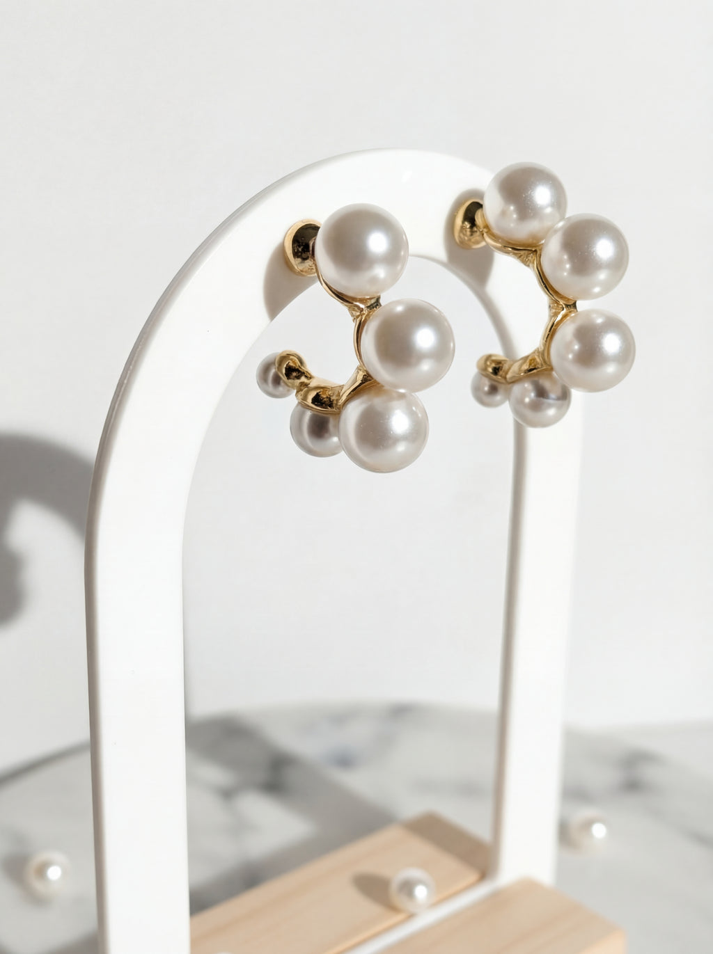 Pearl earrings on a stand with a neutral background