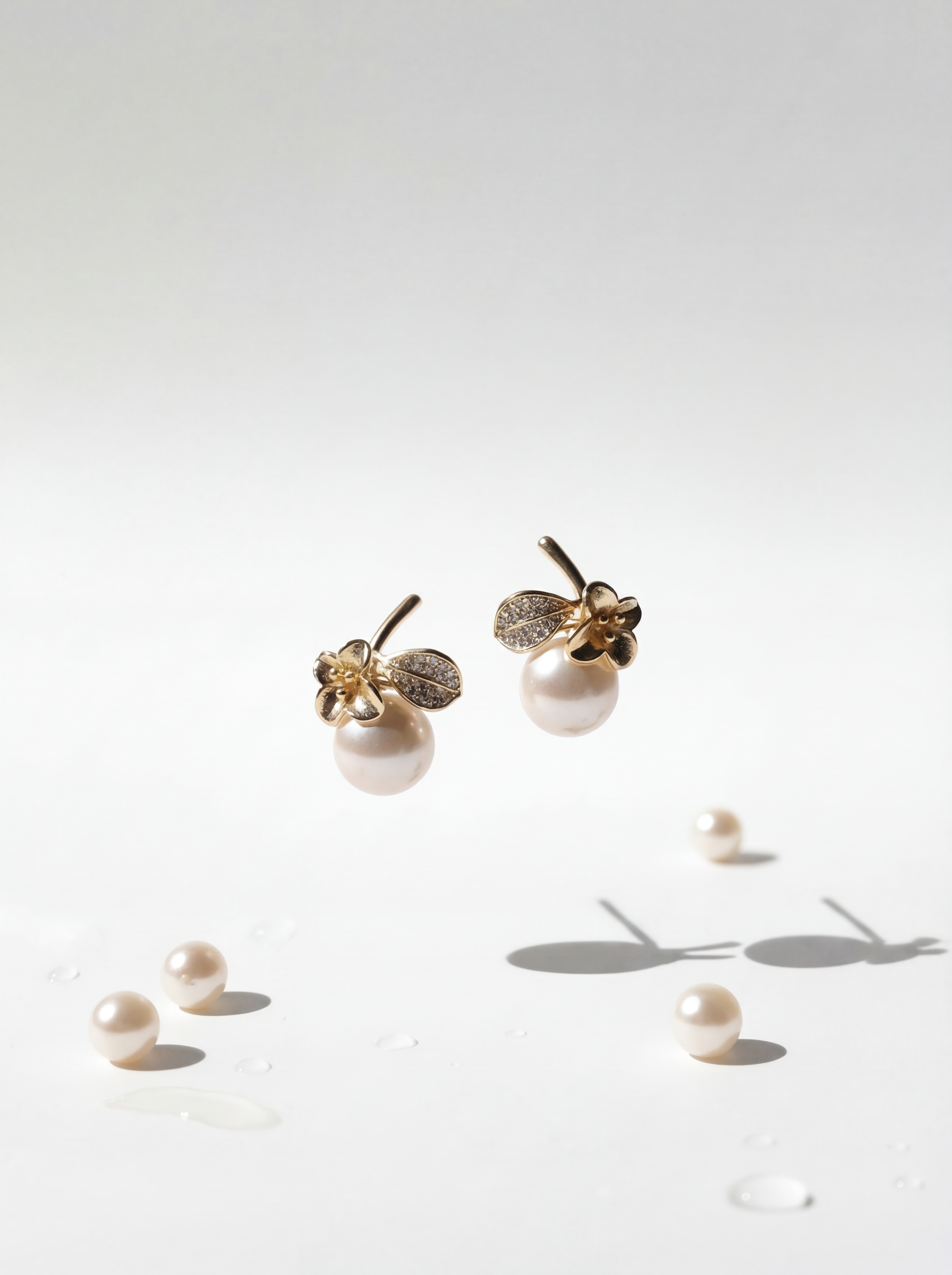 Gold earrings with pearls on a light gray background