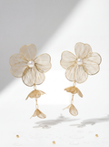 Gold floral earrings with pearl centers on a light gray background