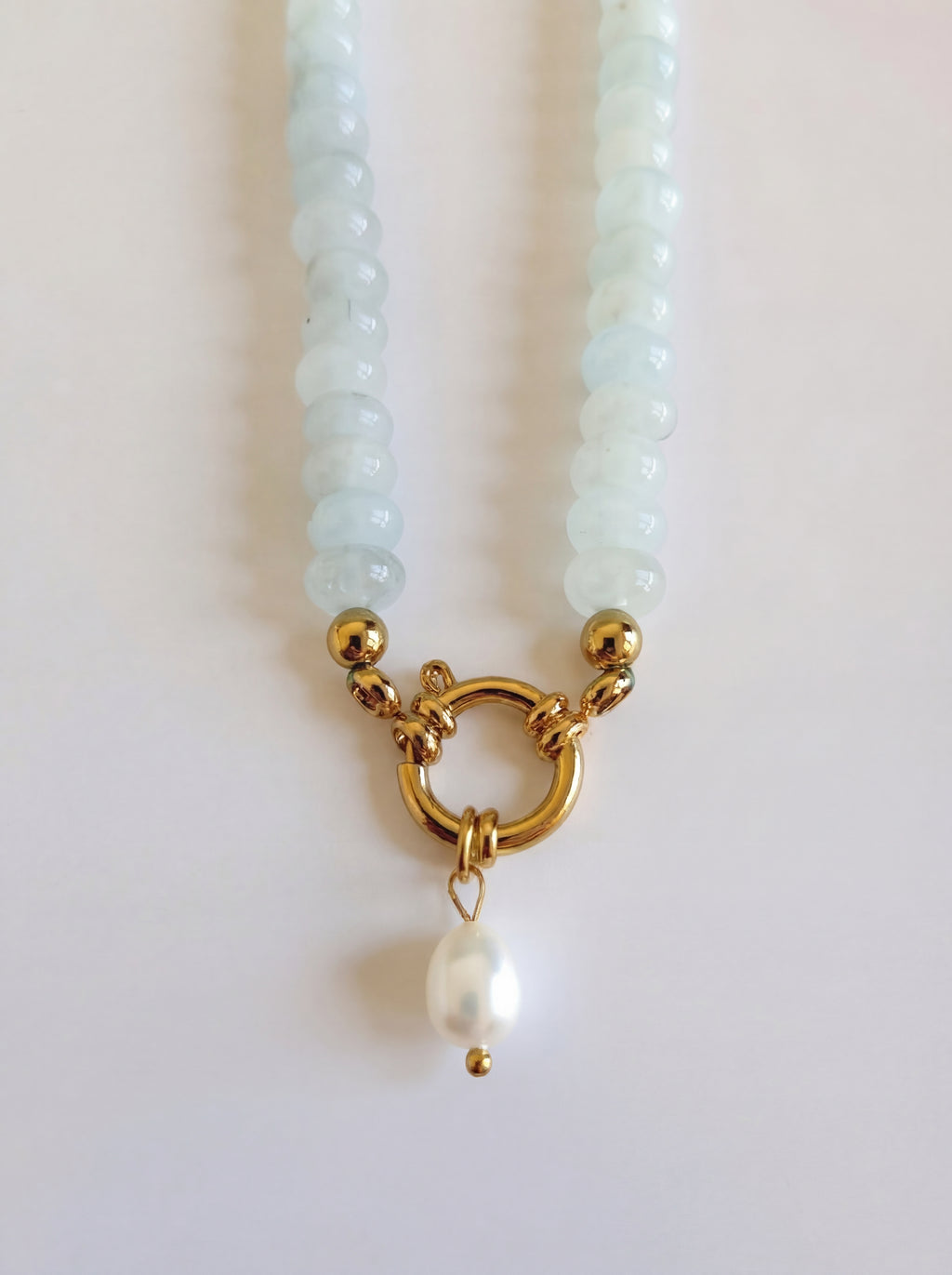 Pearl necklace with a gold clasp and pearl pendant on a light background
