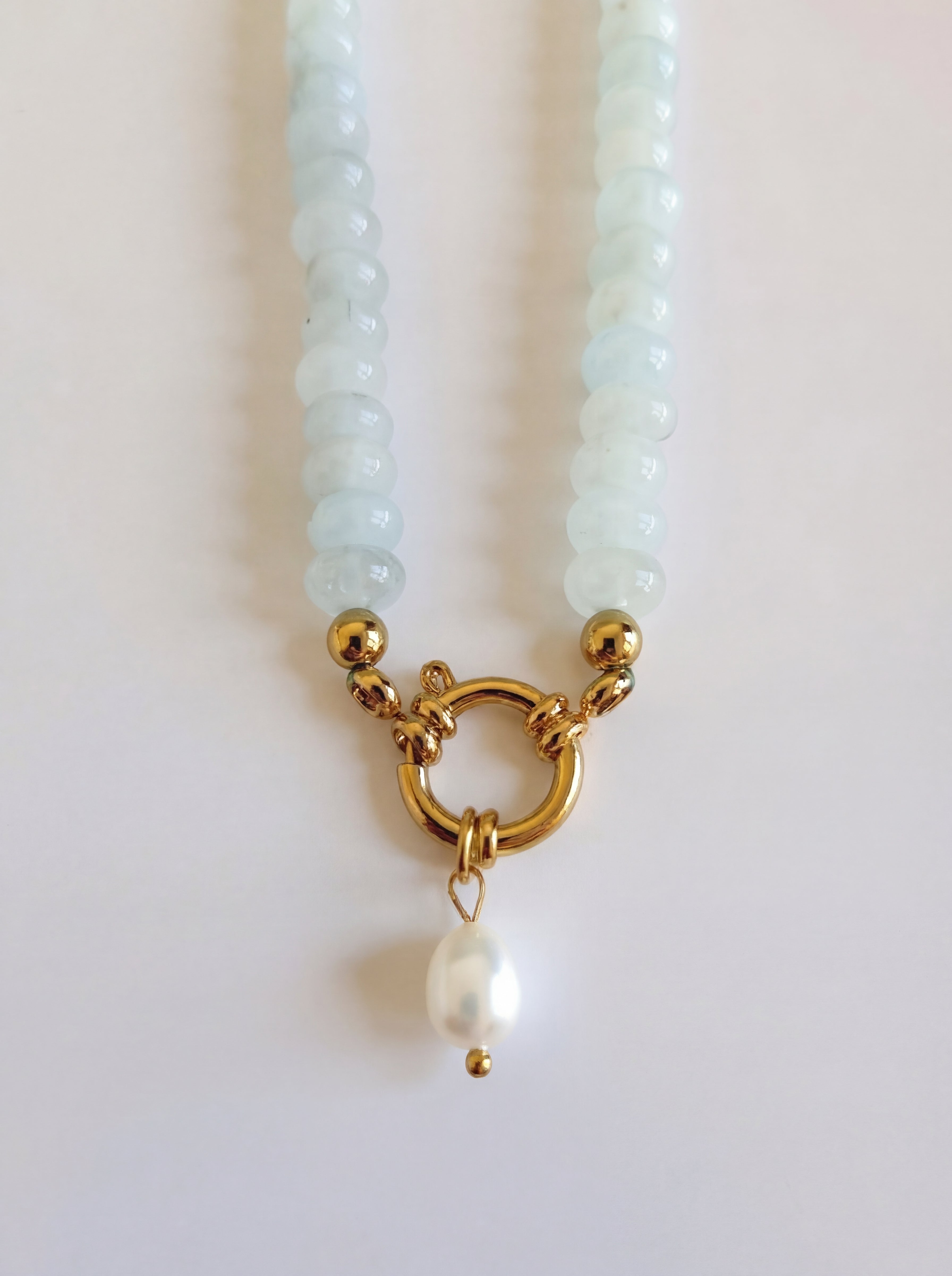 Pearl necklace with a gold clasp and pearl pendant on a light background