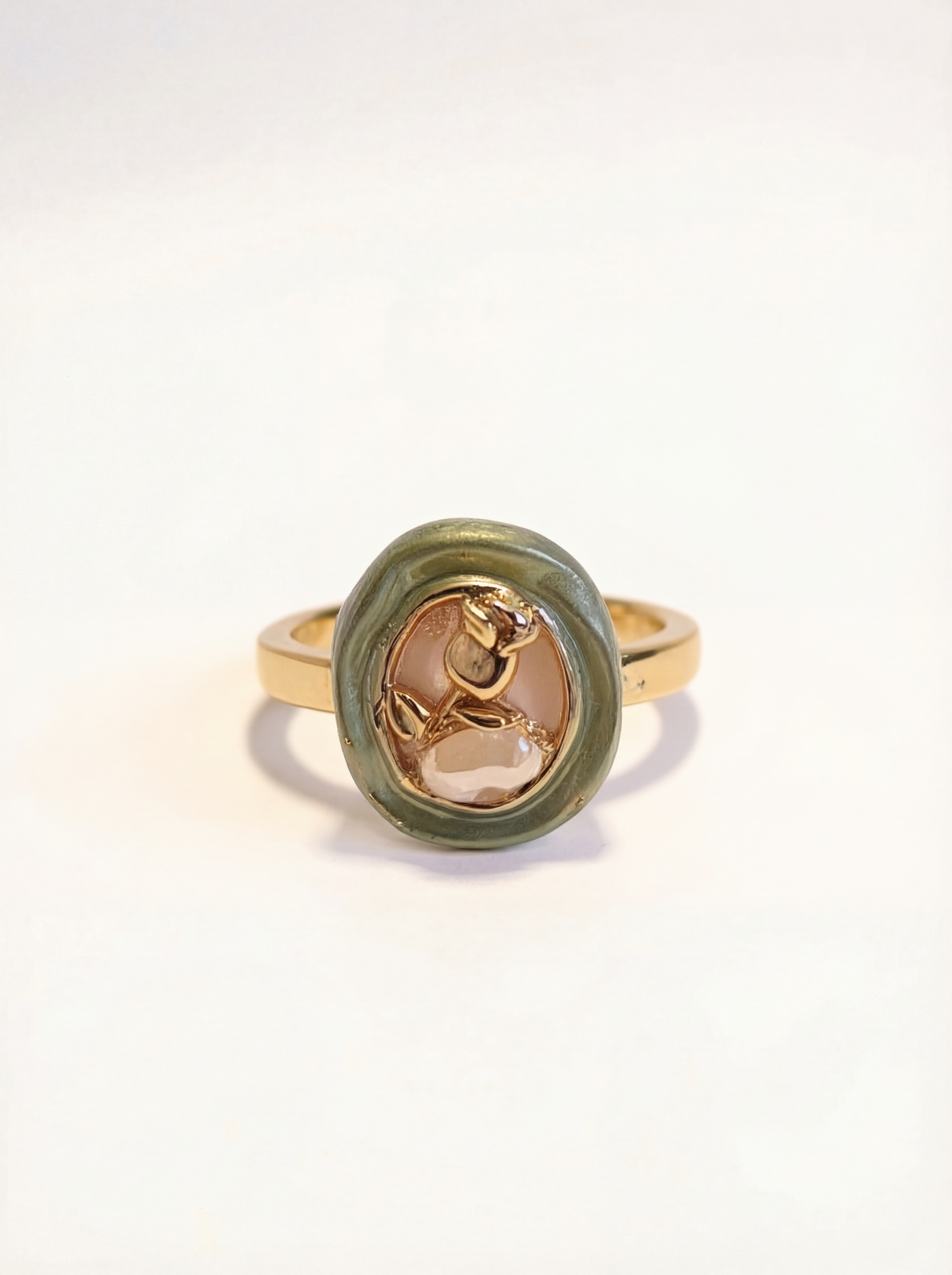 Gold ring with a green stone on a white background