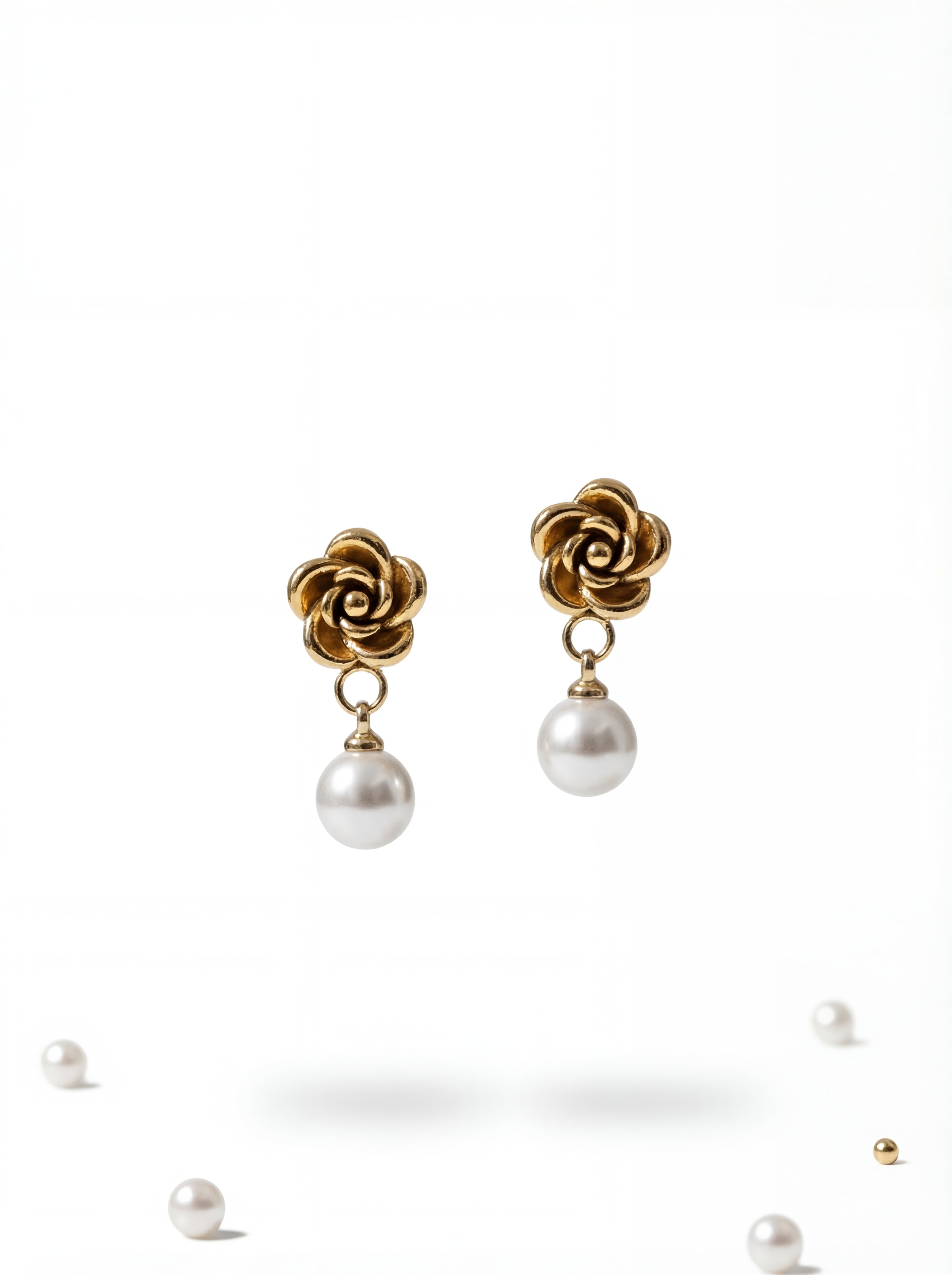 Gold flower-shaped earrings with pearl drops on a white background