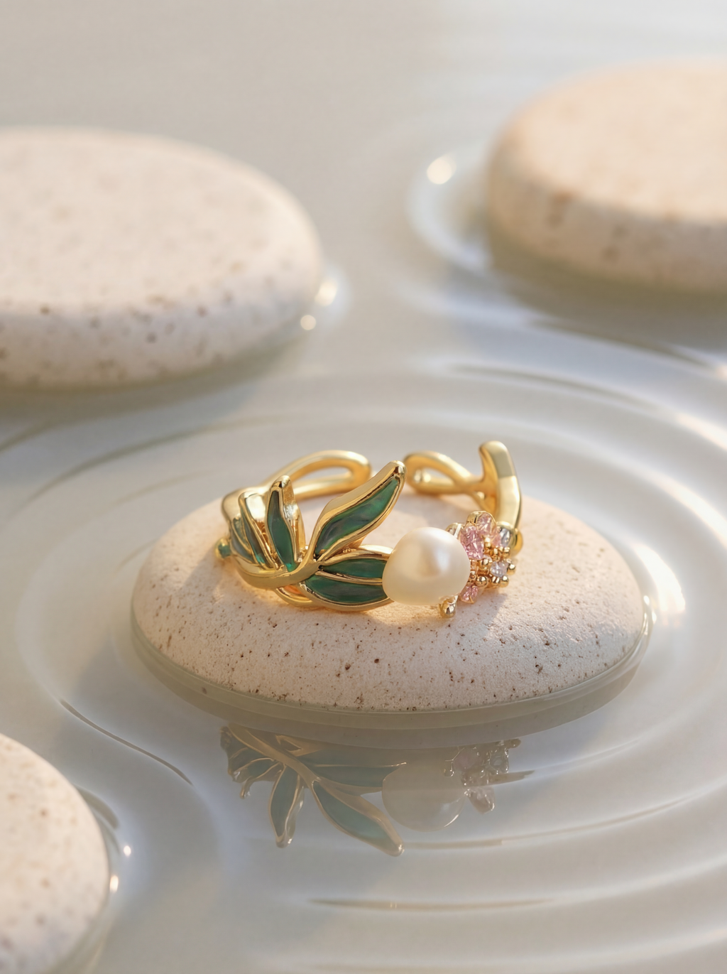 Gold ring with green leaf design and pearl on a stone with water