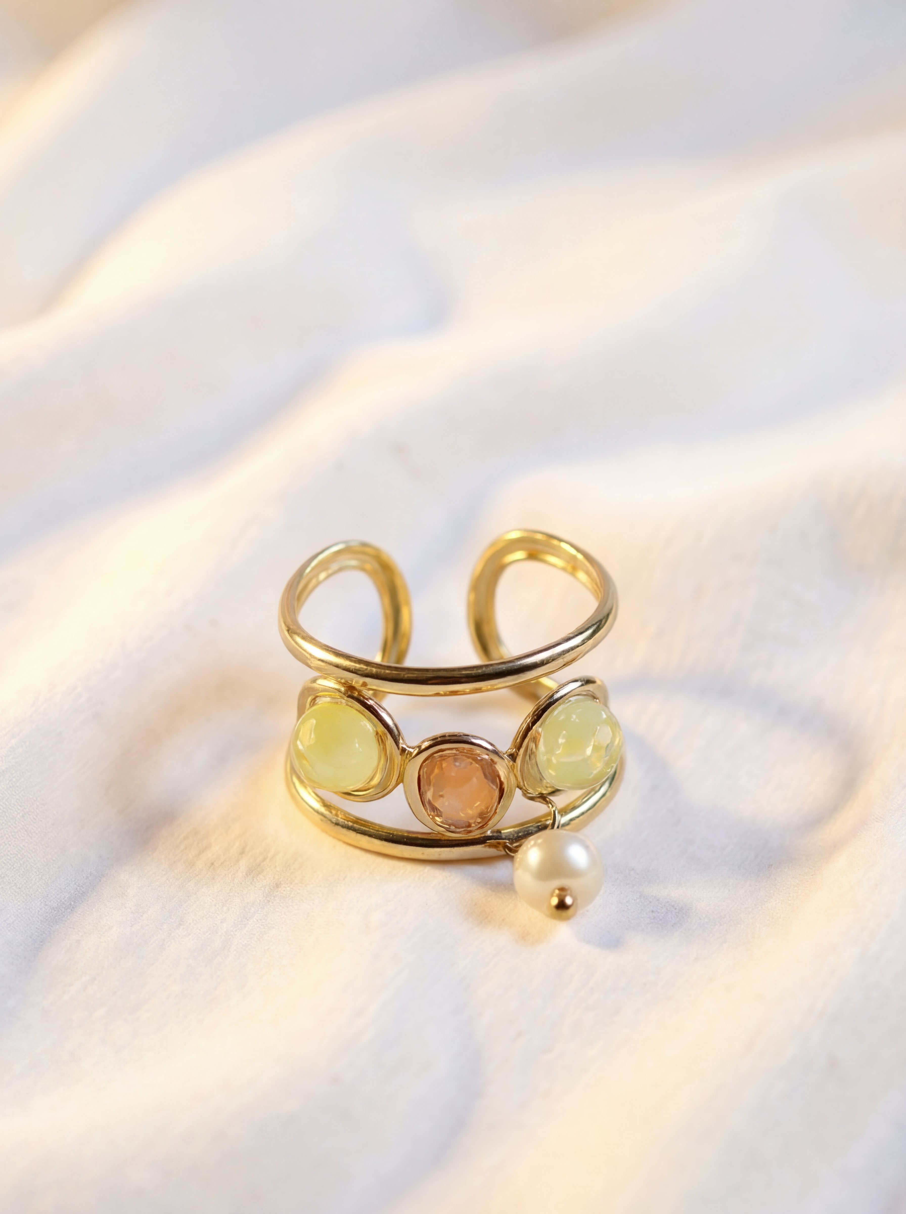 Gold ring with gemstones on a white fabric background