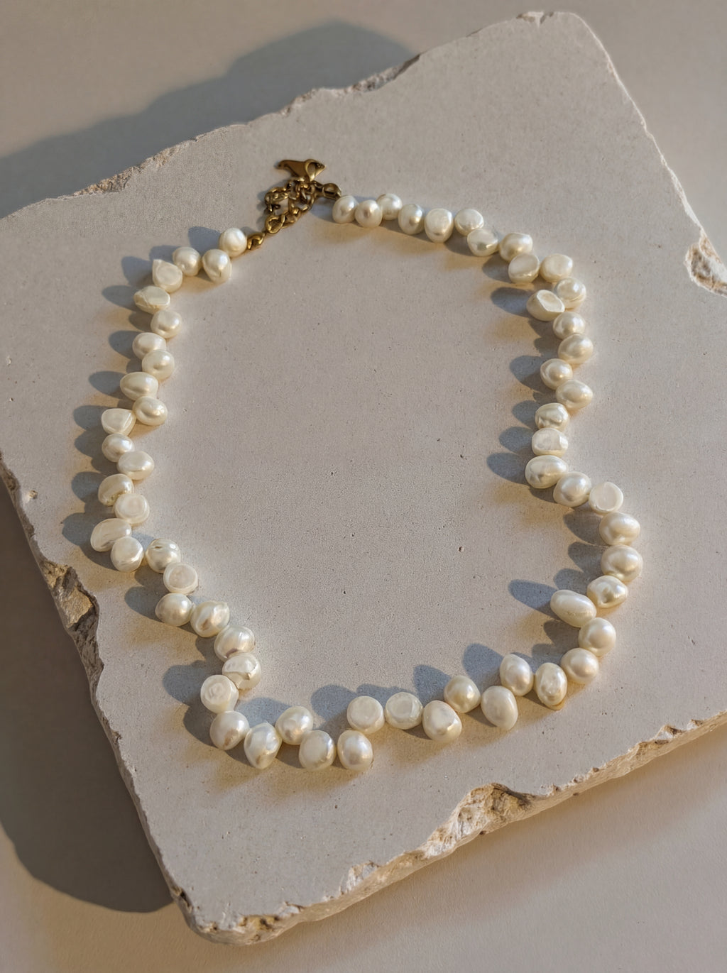 Pearl necklace on a textured stone surface