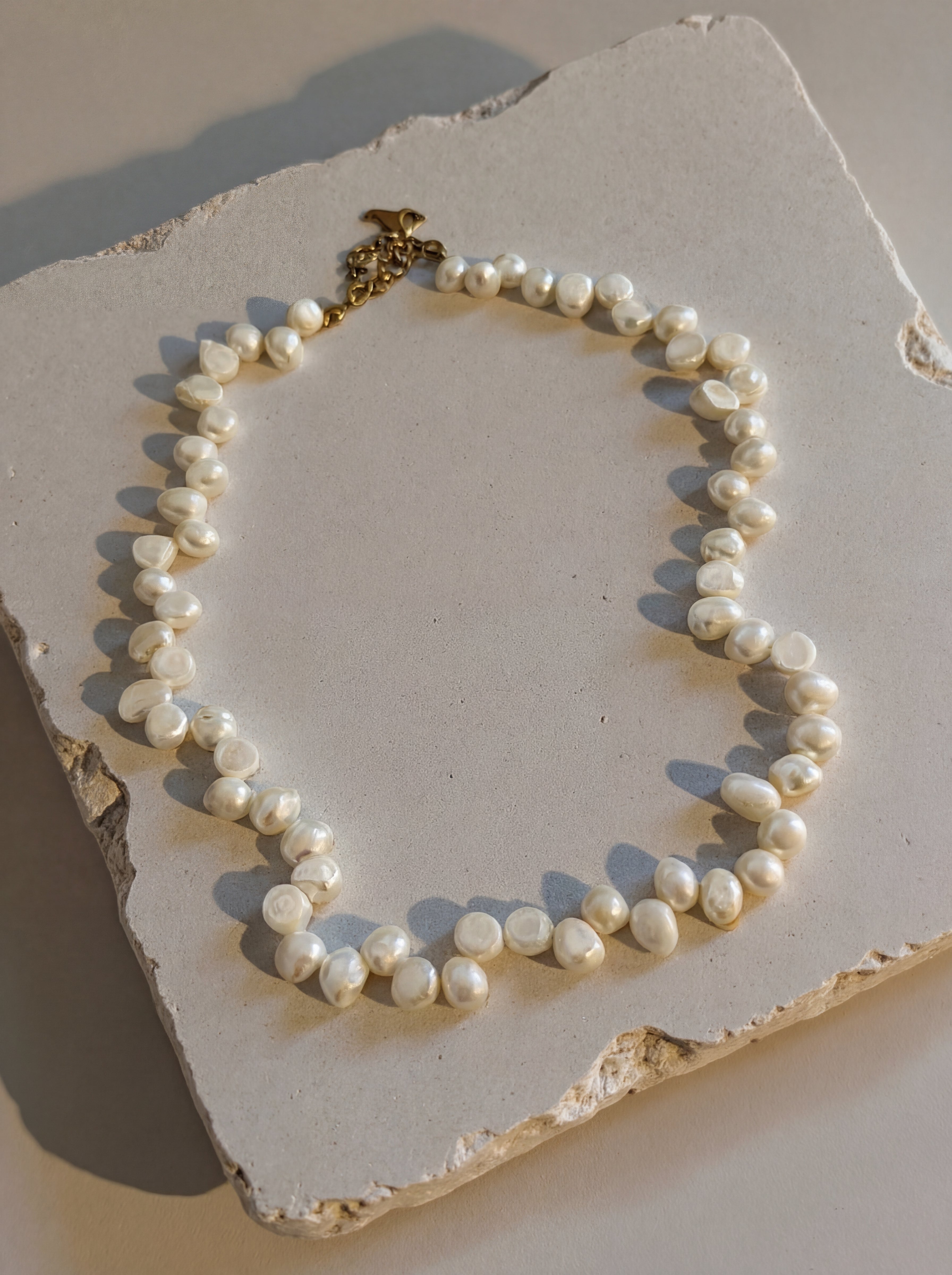 Pearl necklace on a textured stone surface