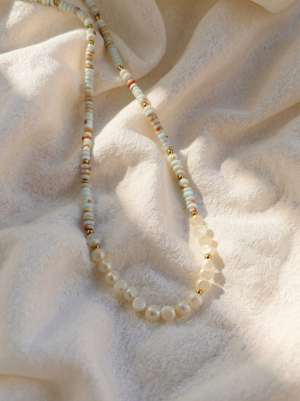 Pearl necklace on a textured beige fabric background