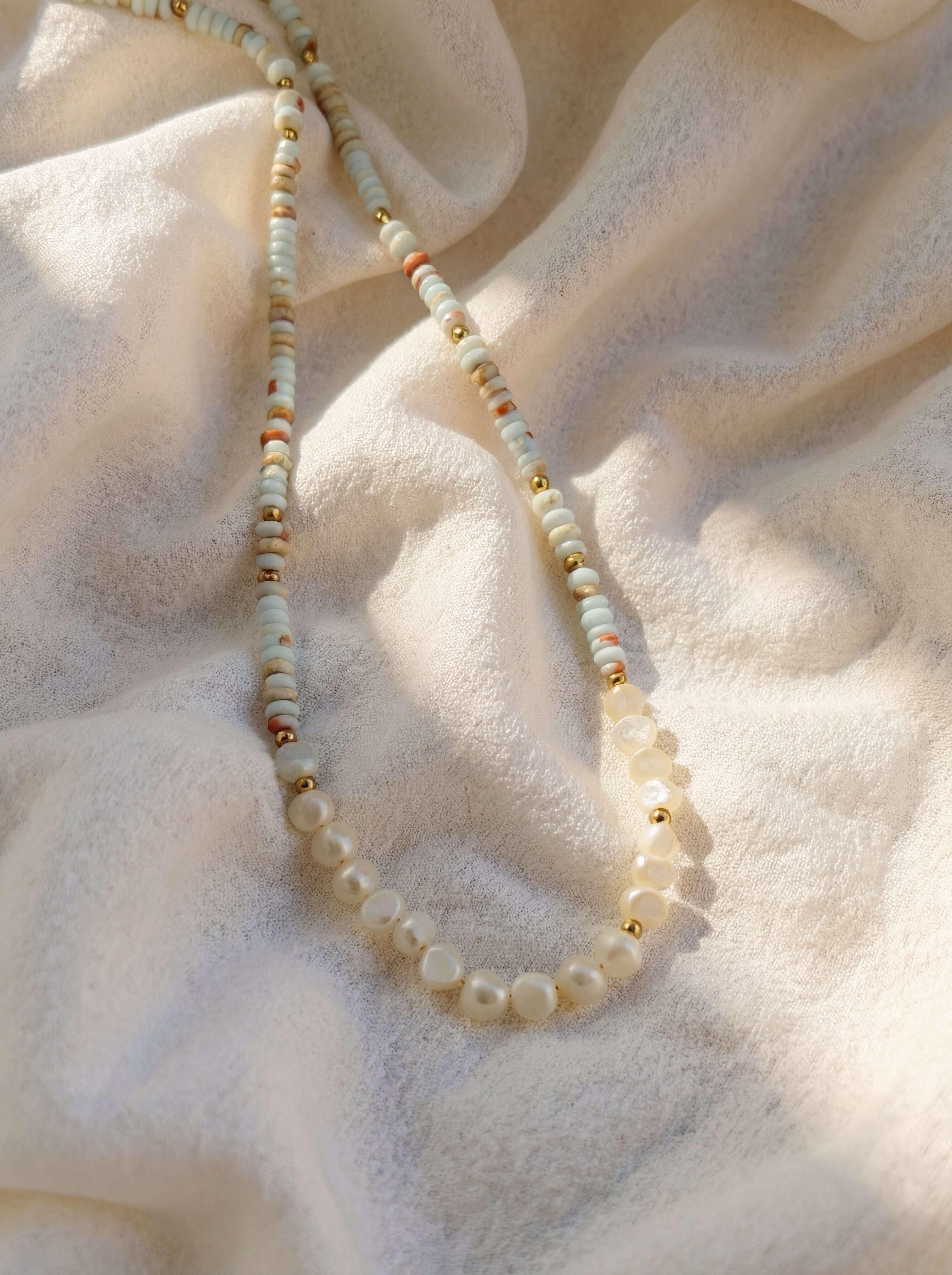 Pearl necklace on a textured beige fabric background