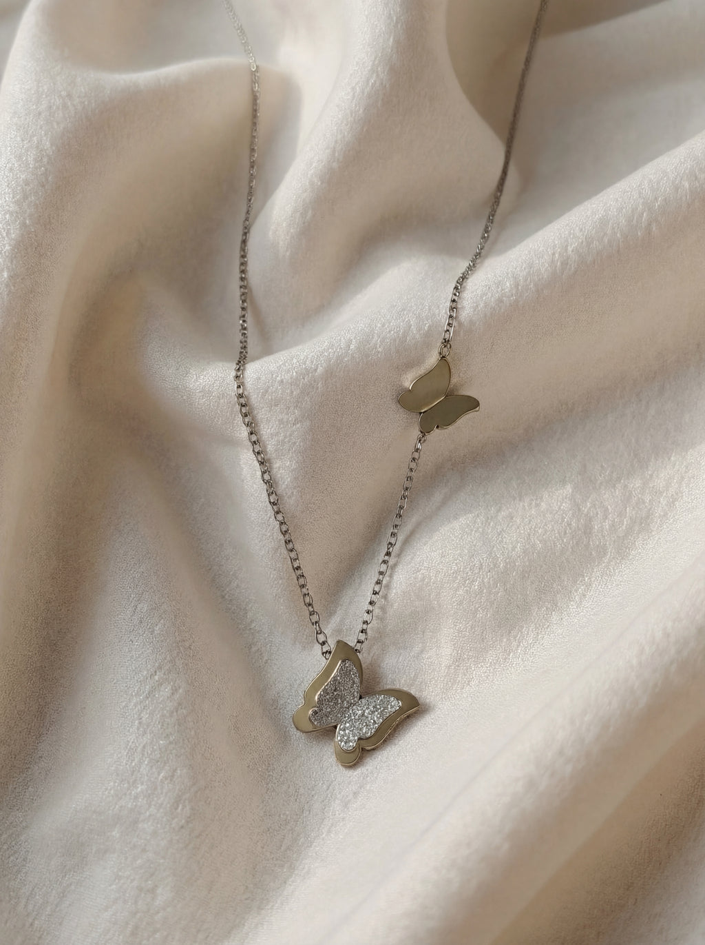 Butterfly-shaped necklace on a soft beige fabric background