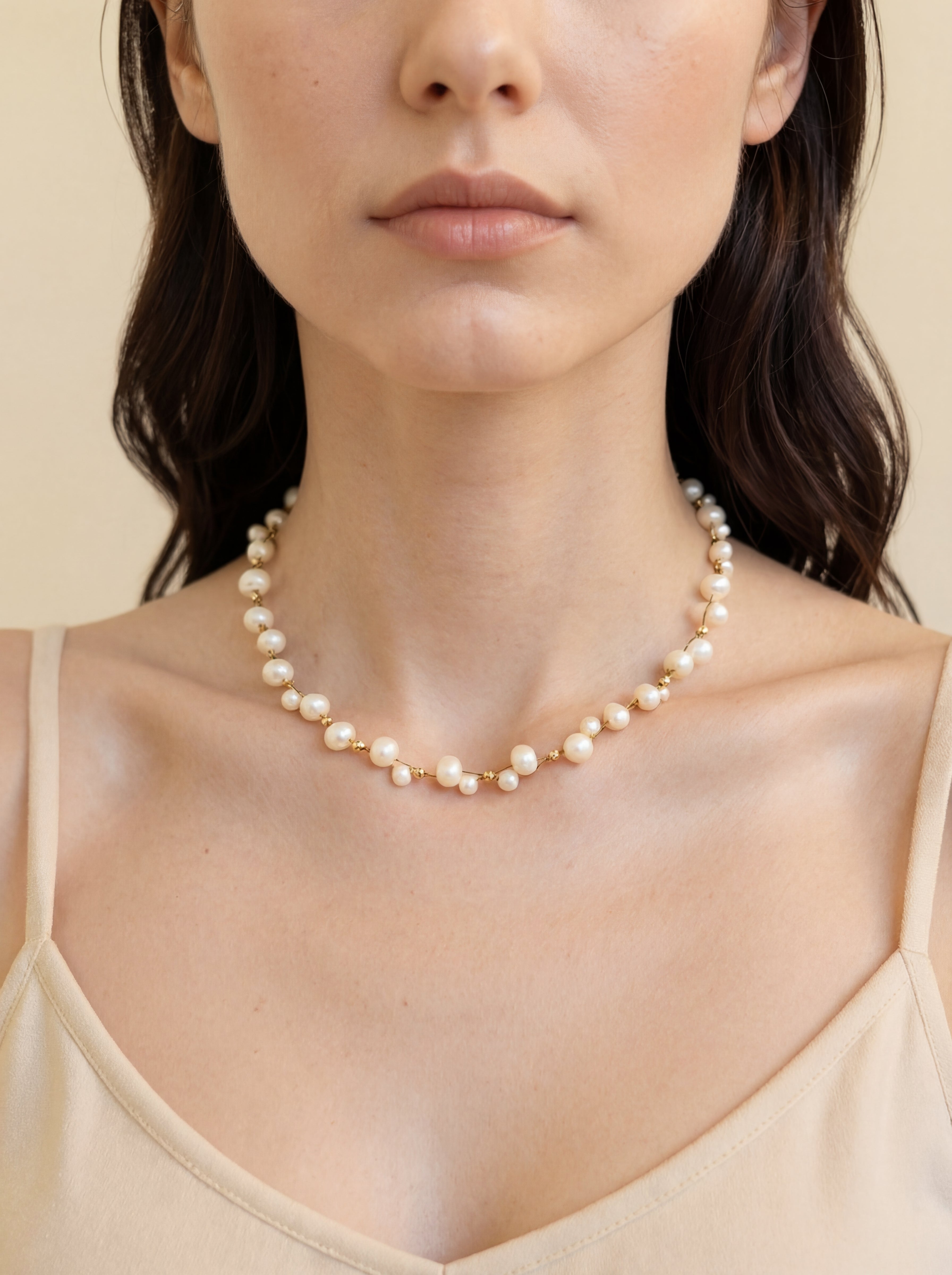 Woman wearing a pearl necklace against a beige background