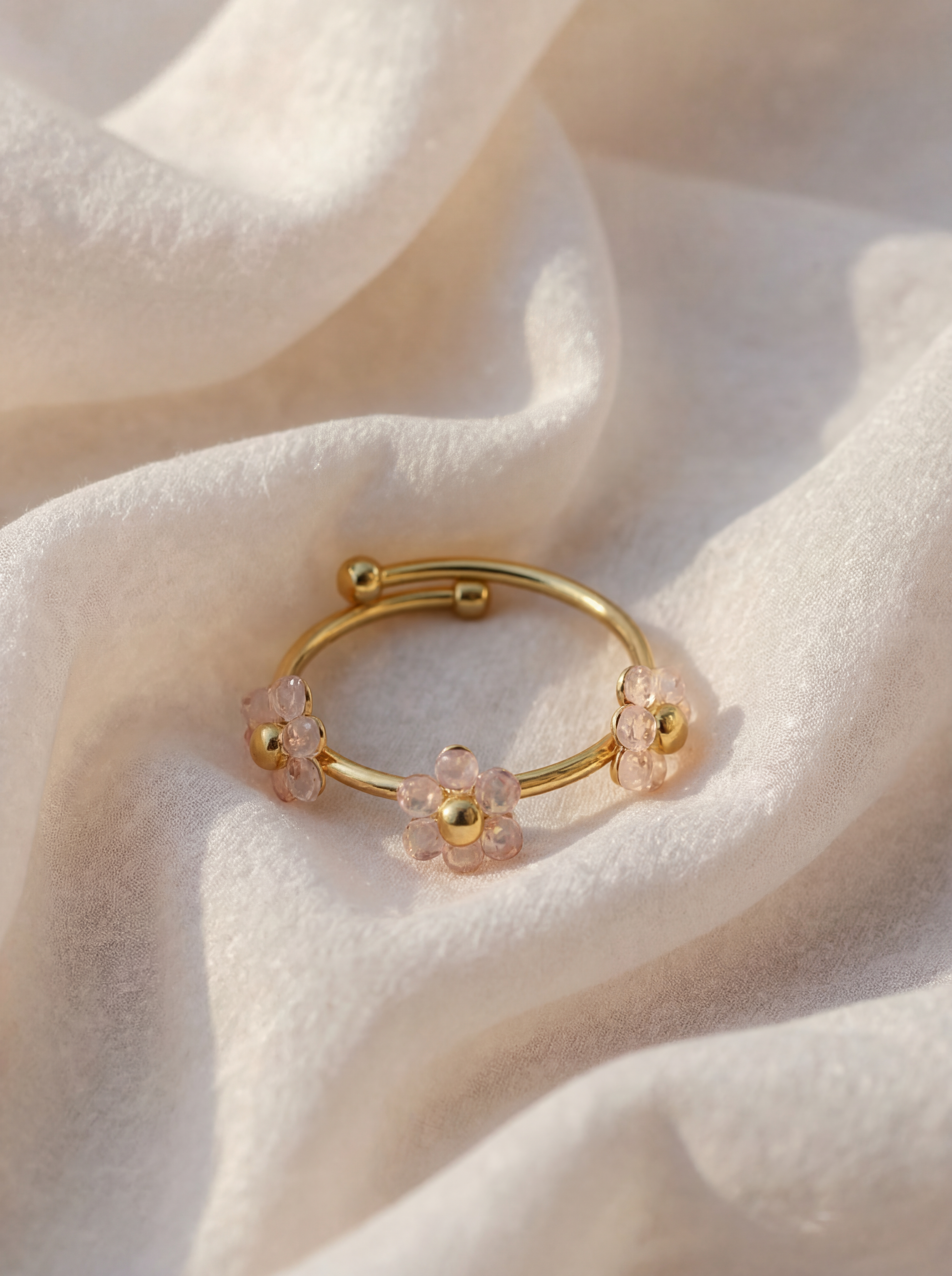 Gold ring with floral designs on a soft white fabric background