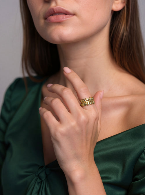 Close-up of a woman wearing a gold ring on a plain background