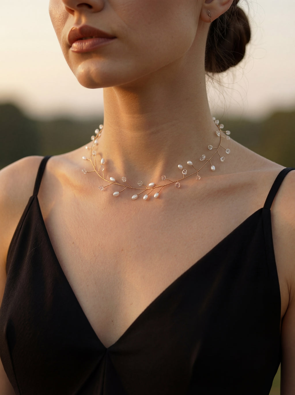 Woman wearing a delicate pearl necklace with a blurred natural background