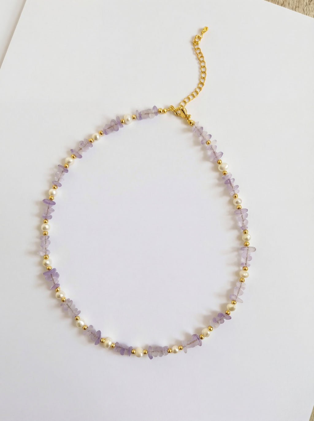 Necklace with purple beads and gold accents on a white background